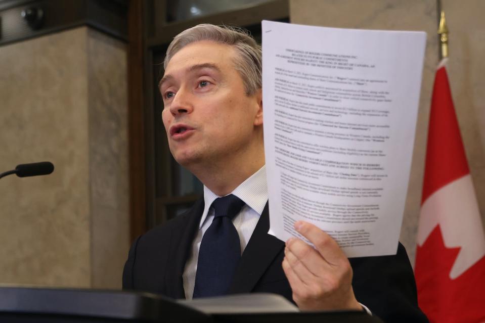 Innovation, Science and Industry Minister François-Philippe Champagne holds up a contract between the telecoms and the federal government as he speaks at a news conference about the Rogers-Shaw merger on Parliament Hill in Ottawa on March 31, 2023. THE CANADIAN PRESS/ Patrick Doyle