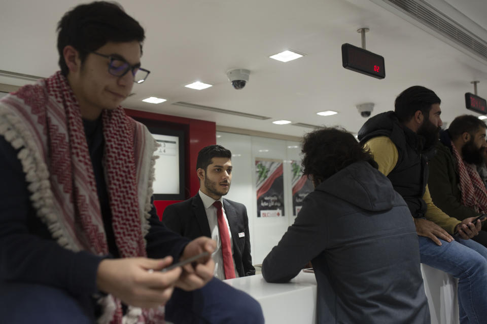 A Lebanese protester speaks with a bank teller during a sit-in at the Hamra branch of BLC Bank Dec. 28, 2019 in Beirut, Lebanon. Dozens of Lebanese protesters held a brief sit-in inside a bank in Beirut and another in the country's south on Saturday, part of their focus on banking policies they complain are inefficient and corrupt.(AP Photo/Maya Alleruzzo)