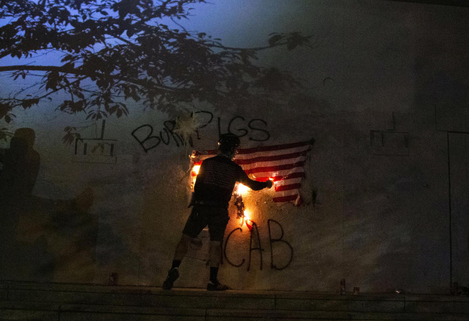 Protesters burn an American flag in downtown Portland, Ore., July 4, 2020. Portland police say more than 12 people were arrested early Sunday after throwing fireworks and mortars as they clashed with police during the latest rally decrying police brutality. (Beth Nakamura/The Oregonian via AP)