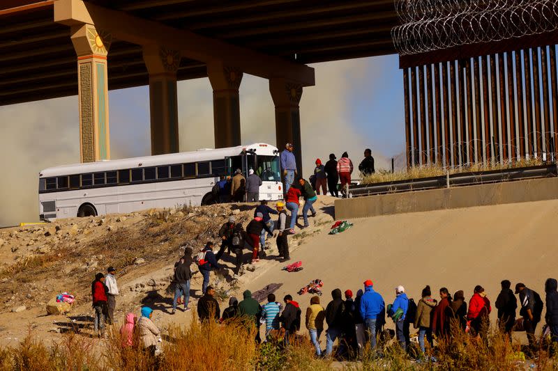 Migrants queue near the border wall after crossing the Rio Bravo river, in Ciudad Juarez