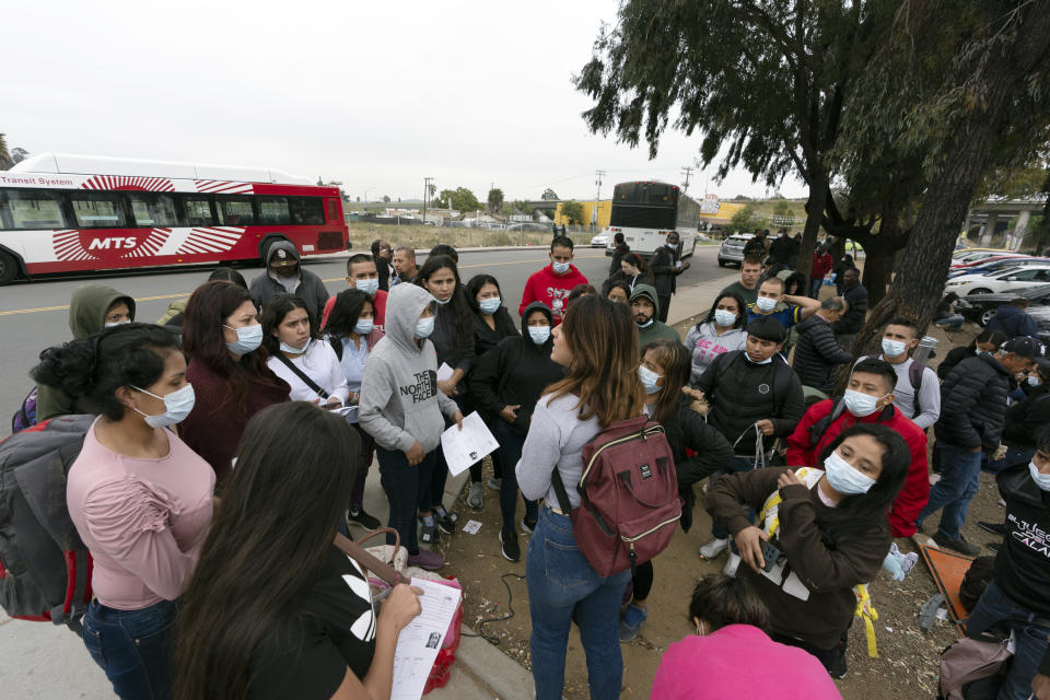 FILE - Migrants listen to a volunteer in a parking lot after being detained and processed for asylum by U.S. authorities, April 12, 2024, in San Diego. A new Biden administration rule aims to speed up asylum processing at the southern border, enabling it to quickly reject a limited group of people believed to have committed serious crimes or who have terrorist links. The change announced May 9 comes during an election year when immigration is a key issue. (AP Photo/Gregory Bull, File)