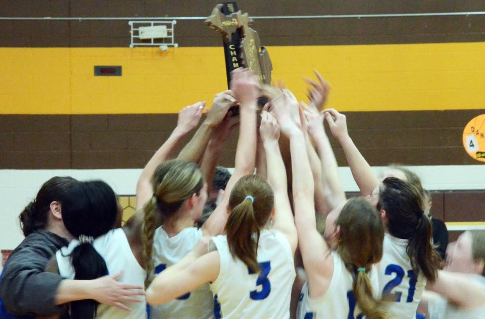 Mackinaw City players celebrate after receiving their Division 4 regional championship trophy in the Pellston High School gym Thursday after a 62-53 win over Inland Lakes.
