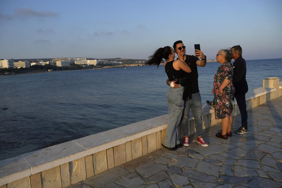 A couple take self photos next from another couple as they watching the sea view at the resort of Ayia Napa in the eastern Mediterranean island of Cyprus, on Tuesday, June 6, 2023. When the U.S. and U.K. in April included a handful of Cypriot nationals and Cyprus-registered companies as part of another global crackdown on 'enablers' helping Russian oligarchs skirt sanctions, the perception that the island nation somehow remains Moscow's financial lackey again loomed large. (AP Photo/Petros Karadjias)