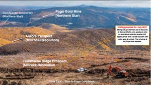 A Fall 2021 photograph showing the Tourmaline Ridge prospect area in the foreground with an excavator digging trenches through shallow overburden to expose bedrock. Northern Star’s Pogo mine and the Goodpaster deposit is visible in the distance five to six kilometers to the east.