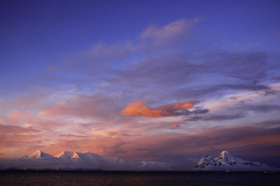 The clouds look pink and red above Antarctica's icebergs