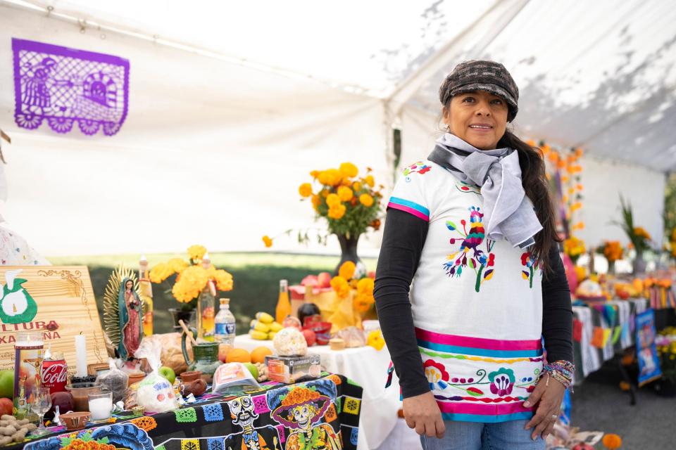 Leticia Vazquez-Smith, a main organizer of the Columbus Day of the Dead festival, stands for a portrait next to shrines for lost family members Saturday at Green Lawn Cemetery.