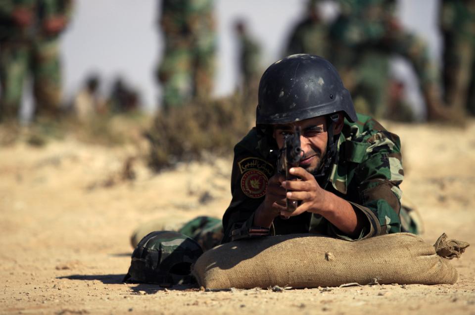 A trainee soldier from the Libyan army takes aim at a target during their graduation exam in Geminis