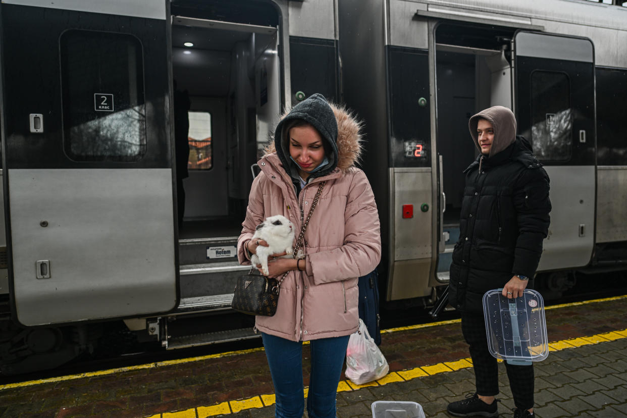 A woman leaving a train carries a pet rabbit in her arms. 