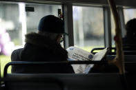 A man reads a newspaper with an article about COVID-19 as he sits on a bus during England's second coronavirus lockdown in London, Tuesday, Dec. 1, 2020. England's second coronavirus lockdown is due to end tomorrow to be replaced by a three-tier system. (AP Photo/Matt Dunham)