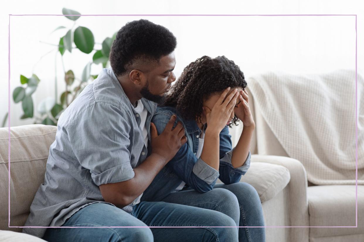  Husband consoling upset wife on the sofa. 