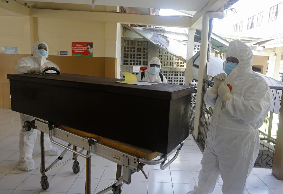 Health workers in protective suits prepare to take the body of a COVID-19 victim at a hospital in Denpasar, Bali, Indonesia on Thursday, July 15, 2021. The world's fourth most populous country has been hit hard by an explosion of COVID-19 cases that have strained hospitals on the main island of Java. (AP Photo/Firdia Lisnawati)