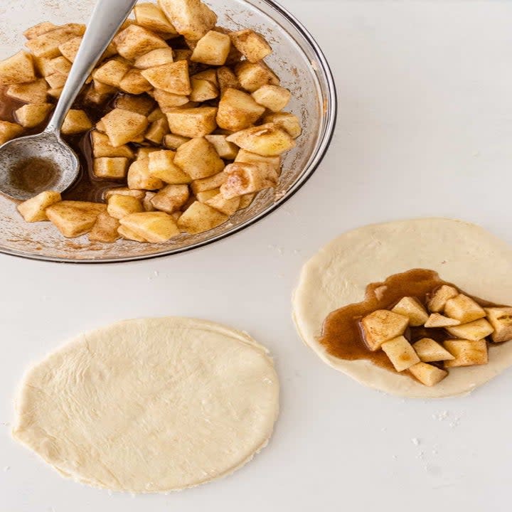 Putting apple filling into pie dough.