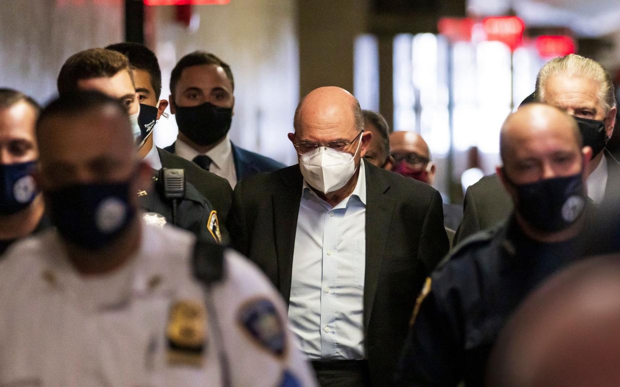 Allen Weisselberg (C), the chief financial officer for the Trump Organization, is escorted by police officers into a court hearing wearing handcuffs - Shutterstock