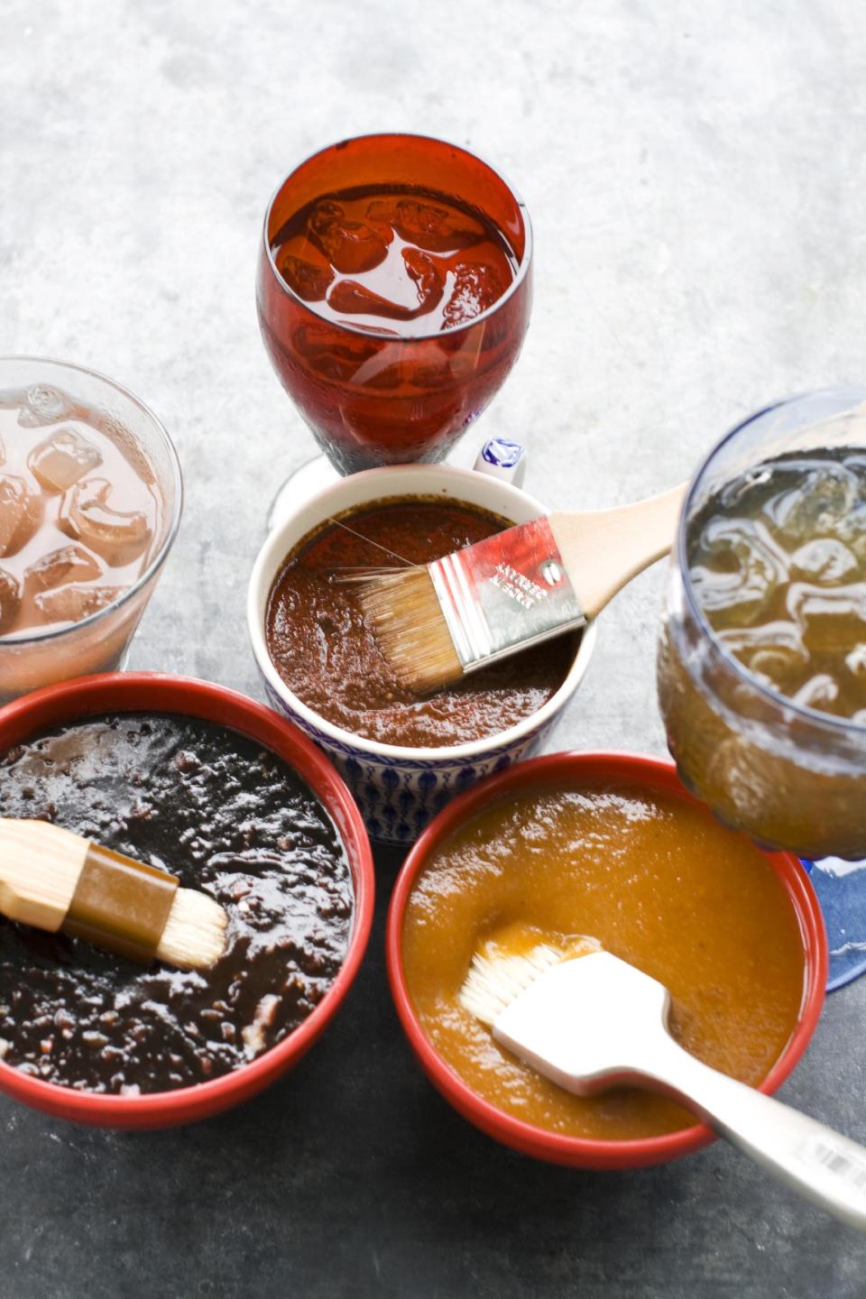 In this image taken on June 10, 2013, from top clockwise, recado rojo, tangy apricot barbecue sauce, and balsamic strawberry jalapeno barbecue sauce are shown with cocktails in Concord, N.H. (AP Photo/Matthew Mead)