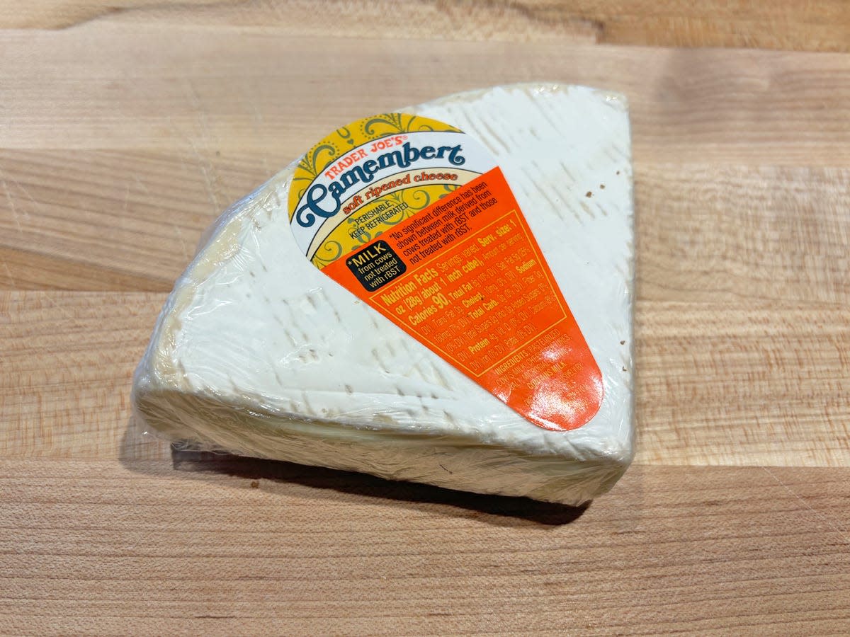 White wedge of cheese with a yellow and orange label reading "Trader Joe's Camembert"