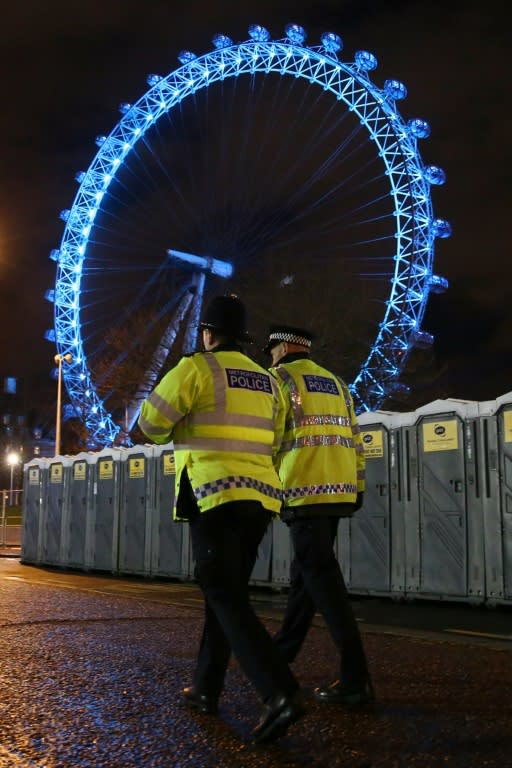 Police officers walk past portaloos in the shadow of the London Eye ahead of the New Year's Eve fireworks