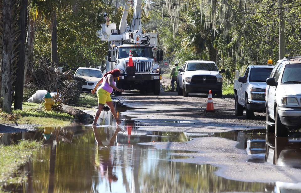 Natalie Hawkins-McGill wades through a lingering puddle on her way to talk with her neighbors on Fulton Street in Daytona Beach's Midtown neighborhood, an area hard-hit by Tropical Storm Ian. On Sunday, Fulton Street residents were still waiting for their power to be restored.