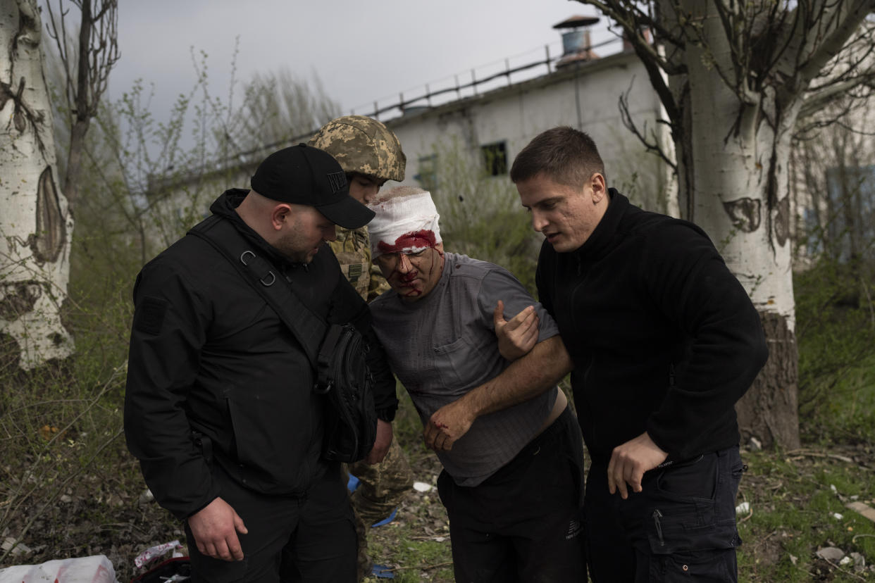 An injured man receives help following a Russian bombing of a factory in Kramatorsk, eastern Ukraine, Tuesday, April 19, 2022, that killed at least one person and injured three others. (AP Photo/Petros Giannakouris)