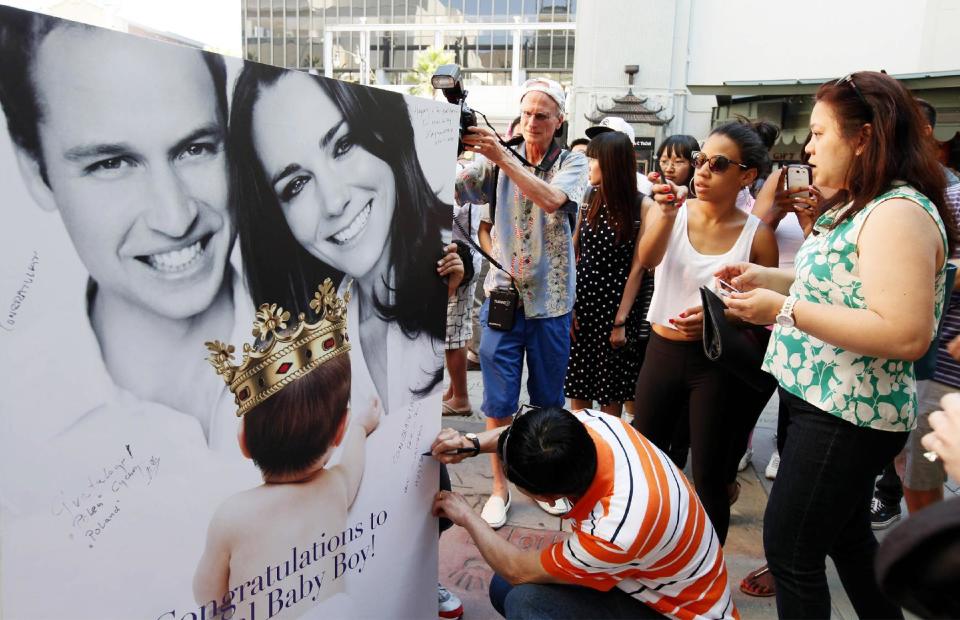 Fans and tourists sign a giant card congratulating Britain's Prince William and Kate, Duchess of Cambridge, on the birth of their baby boy Tuesday, July 23, 2013 outside the TCL Chinese Theatre in the Hollywood district of Los Angeles in Los Angeles Tuesday, July 23, 2013. (AP Photo/Nick Ut)