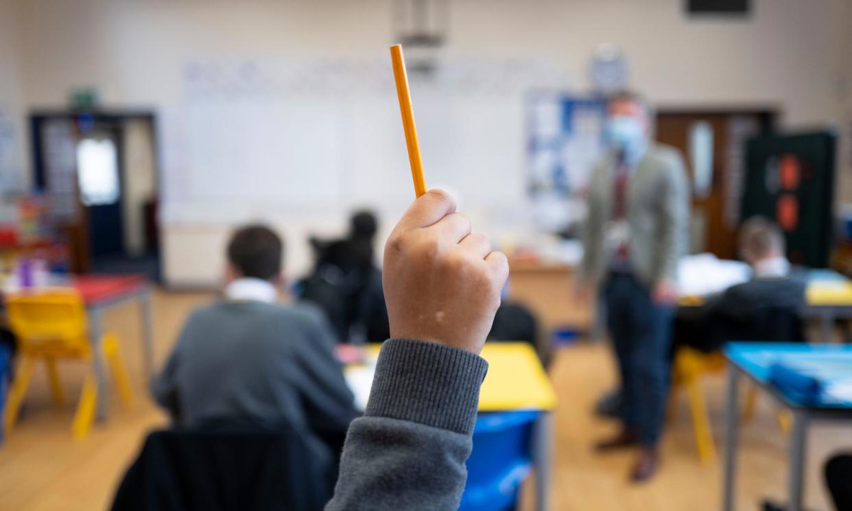 <span>A pupil raises their hand during a lesson at Whitchurch high school in Cardiff, Wales, 2021. </span><span>Photograph: Matthew Horwood/Getty Images</span>