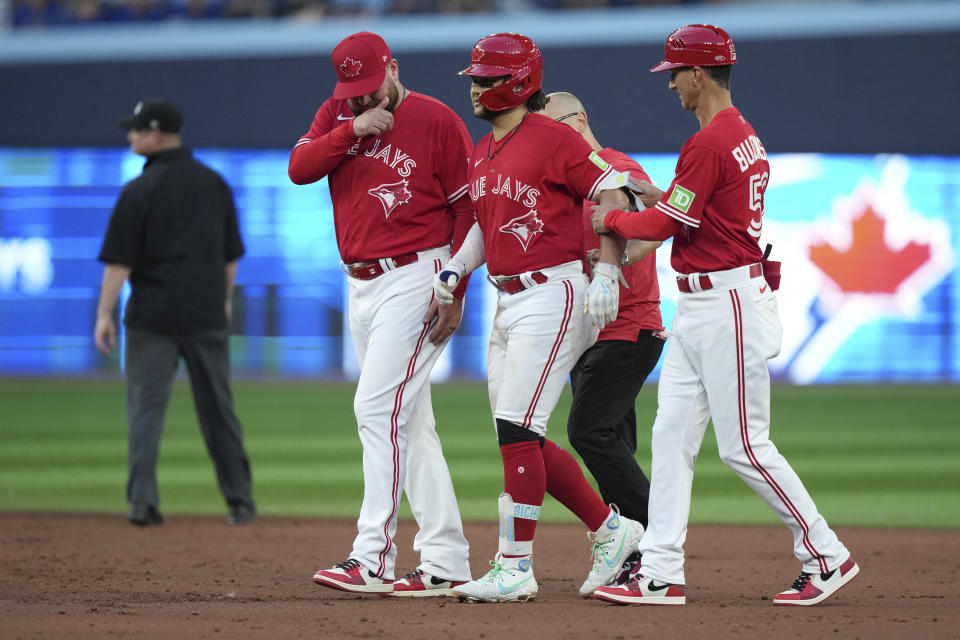 Toronto Blue Jays' Bo Bichette, center, is helped off the field by Blue Jays manager John Schneider, front left, and first base coach Mark Budzinski, right, after taking an injury during fourth-inning baseball game action against the Baltimore Orioles in Toronto, Monday, July 31, 2023. (Nathan Denette/The Canadian Press via AP)