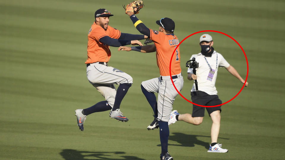 An MLB employee is pictured behind Houston Astros players Carlos Correa and George Springer.