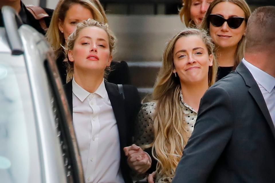 Amber Heard (L) leaves hand-in-hand with her sister Whitney Henriquez (R) after she testified in court in the libel case by Heard's ex-husband Johnny Depp against at British tabloid, in London on July 24, 2020.