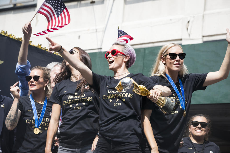 MANHATTAN, NY - JULY 10: Megan Rapinoe #15 of United States points to the crowds as she holds the 2019 FIFA World Cup Champion Trophy, Ashlyn Harris #18 of United States Alex Morgan #13 of United States and Allie Long #20 of United States ride on the World Champions float as it rides down Broadway for the Ticker Tape through the Canyon of Heroes.  This celebration was put on by the City of Manhattan to honor the team winning the 2019 FIFA World Cup Championship title, their fourth, played in France against Netherlands, at the City Hall Ceremony in the Manhattan borough of New York on July 10, 2019, USA.  (Photo by Ira L. Black/Corbis via Getty Images)