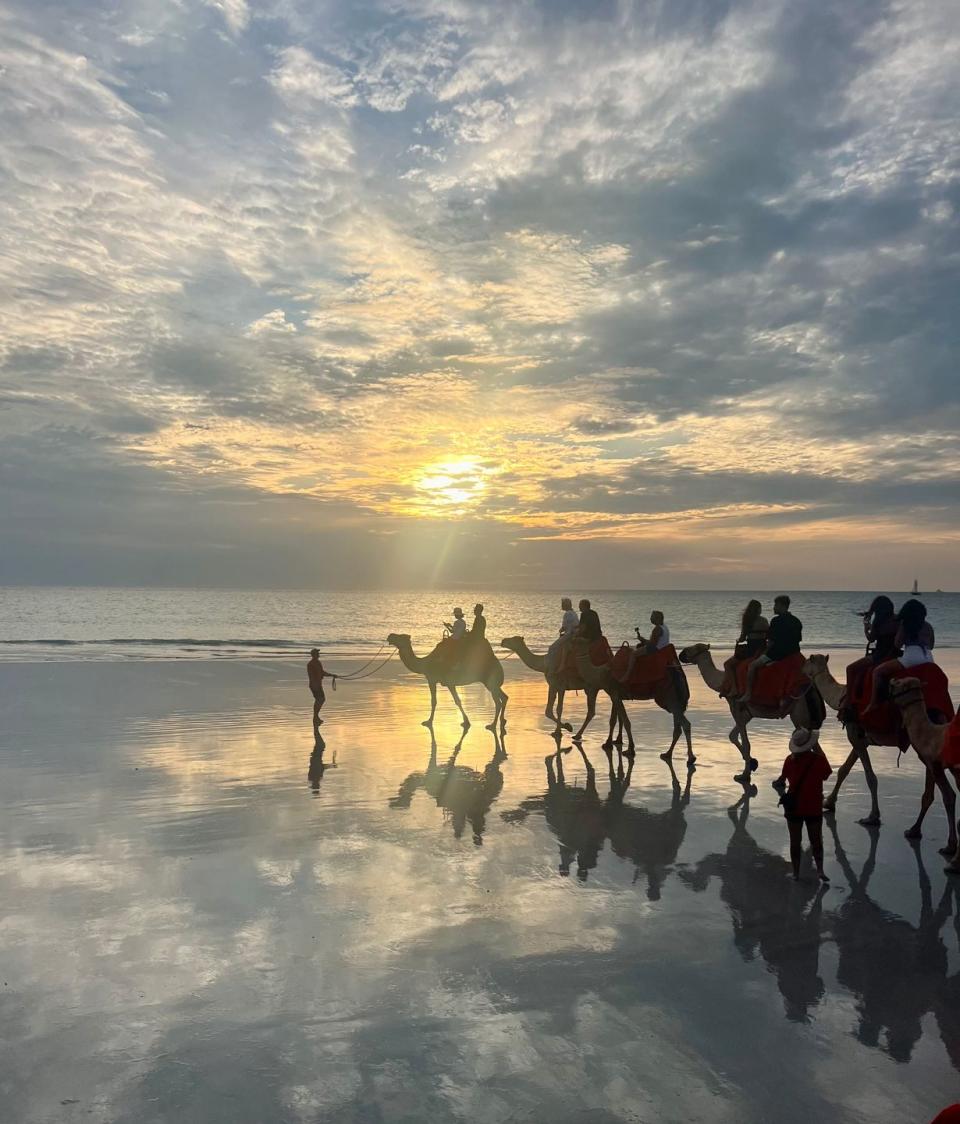 a group of people riding horses on a beach