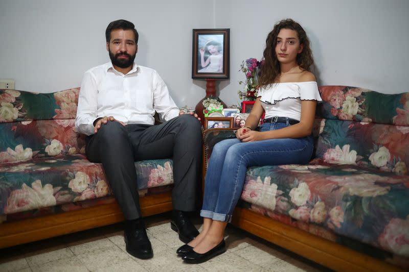 Elie Hasrouty and Tatiana Hasrouty pose for a photograph as they wait for news about their father Ghassan Hasrouty, a missing silo employee, following Tuesday's blast in Beirut's port area