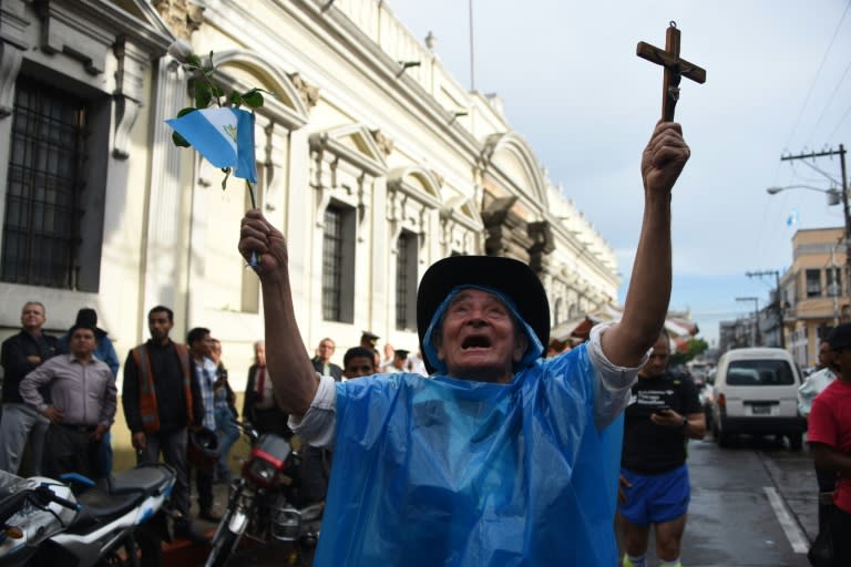 A man celebrates with a cross and a national flag after the Congress voted unanimously to strip embattled President Otto Perez's immunity in Guatemala City on September 1, 2015