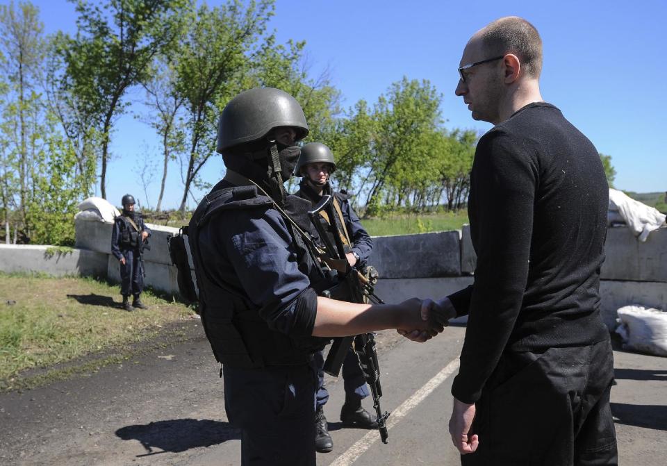 FILE - In this May 7, 2014 file photo, Ukrainian Prime Minister Arseniy Yatsenyuk, right, shakes hands with Ukrainian soldiers at a block post on the road at Slovyansk, Ukraine. Yatsenyuk’s interim government is seeking to carry out sweeping reforms to break from a culture of self-interest, cynicism and corruption that left the country on the verge of bankruptcy. (AP Photo/Andrew Kravchenko, Pool, File)