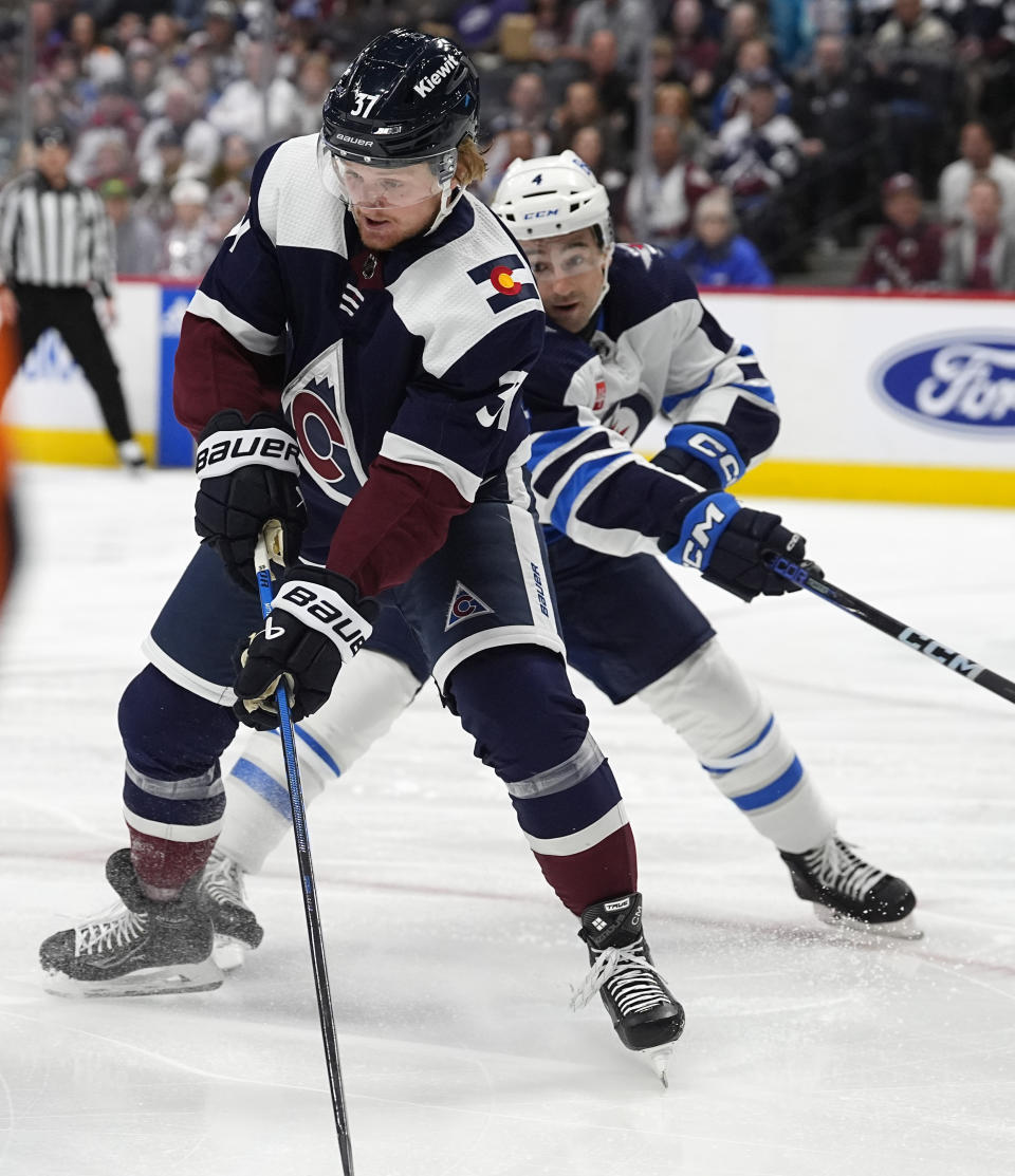 Colorado Avalanche center Casey Mittelstadt, left, looks to pass the puck as Winnipeg Jets defenseman Neal Pionk, right, covers in the first period of an NHL hockey game Saturday, April 13, 2024, in Denver. (AP Photo/David Zalubowski)