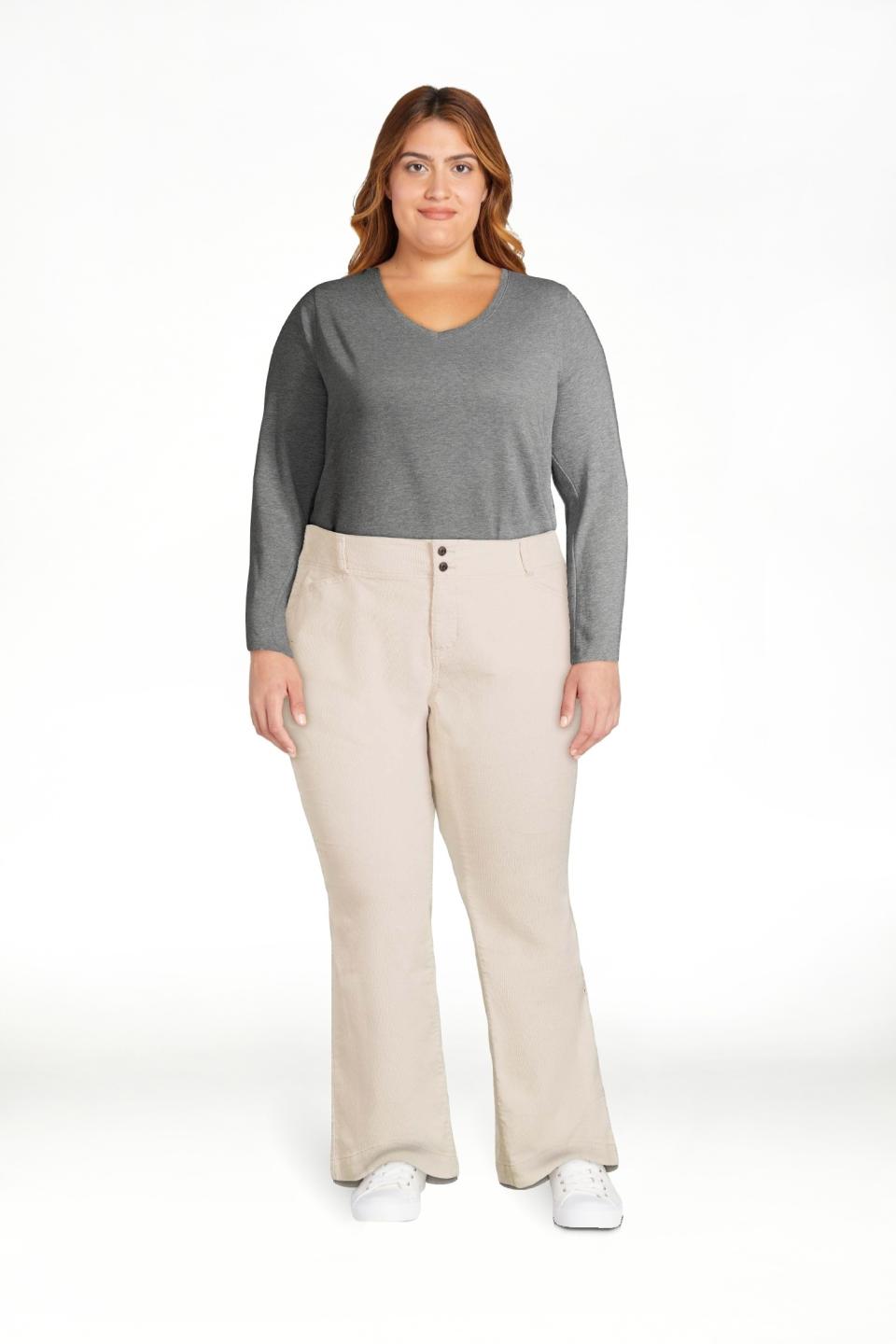 model in V-neck top and casual beige pants stands with hands slightly behind them, paired with white sneakers