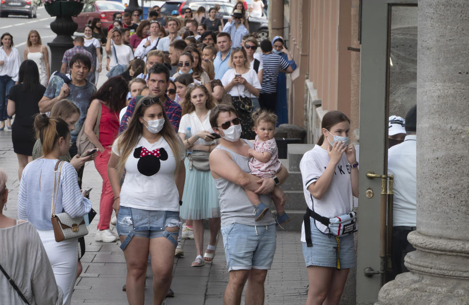 People wearing face masks to protect against coronavirus infection stand in line to enter a clothing store, opened after more than three months lockdown due to coronavirus pandemic, in St.Petersburg, Russia, Tuesday, June 16, 2020. (AP Photo/Dmitri Lovetsky)