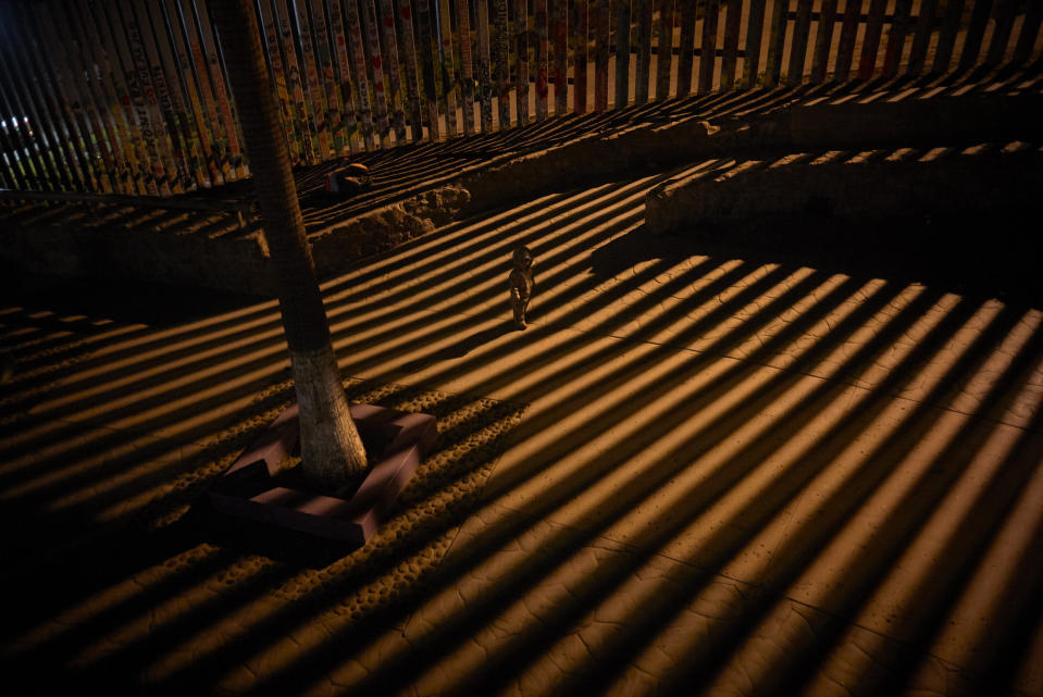 In this Jan. 11, 2019 photo, a boy plays as floodlights from the United States filter through the border wall in Tijuana, Mexico. The partial U.S. government shutdown was on track Friday to become the longest closure in U.S. history as President Donald Trump and nervous Republicans look for a way out of the mess. A solution couldn't come soon enough for federal workers who got pay statements Friday but no pay. (AP Photo/Gregory Bull)
