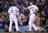 Los Angeles Dodgers' Corey Seager, center, is congratulated by Max Muncy, left, after hitting a two-run home run as Philadelphia Phillies catcher J.T. Realmuto kneels at the plate during the fifth inning of a baseball game Friday, May 31, 2019, in Los Angeles. (AP Photo/Mark J. Terrill)