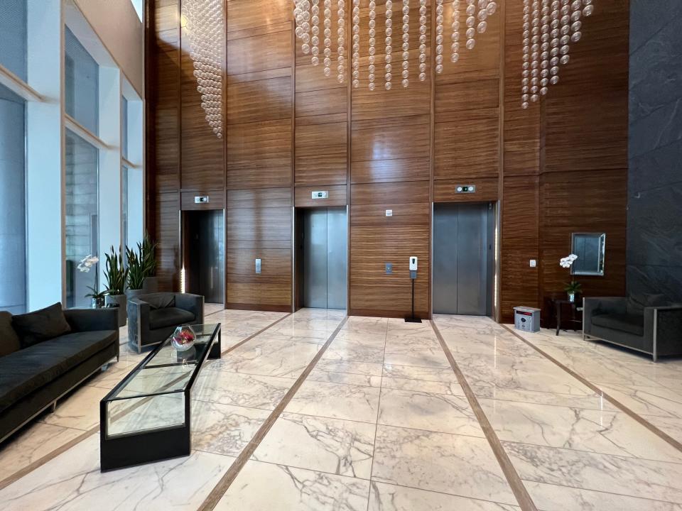 A small lobby area with marble floors, a couch, and three elevators.