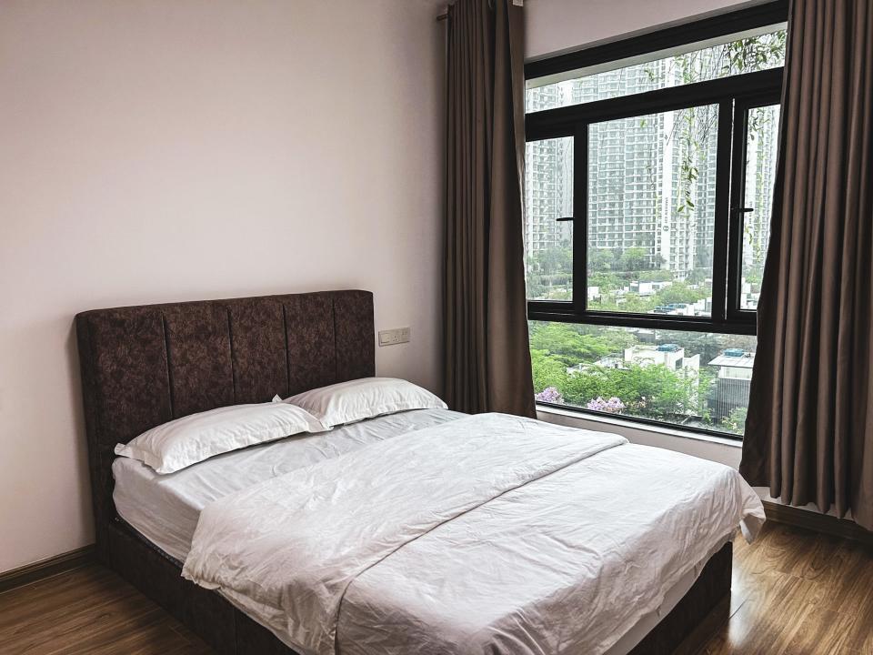 a bedroom next to a window showing forest city's beach