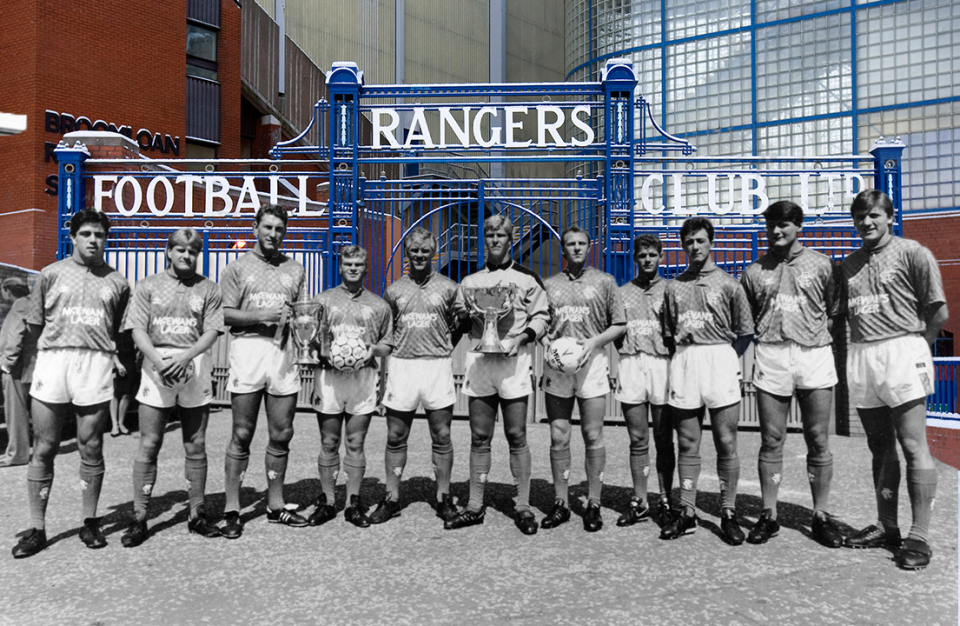 <p>In the image, the Rangers squad featuring Derek Ferguson, John McGregor and Jimmy Philips pose outside the famous Ibrox gates to show off the Scottish Premier League and League Cup trophies that they won in the 1986/87 season. </p>