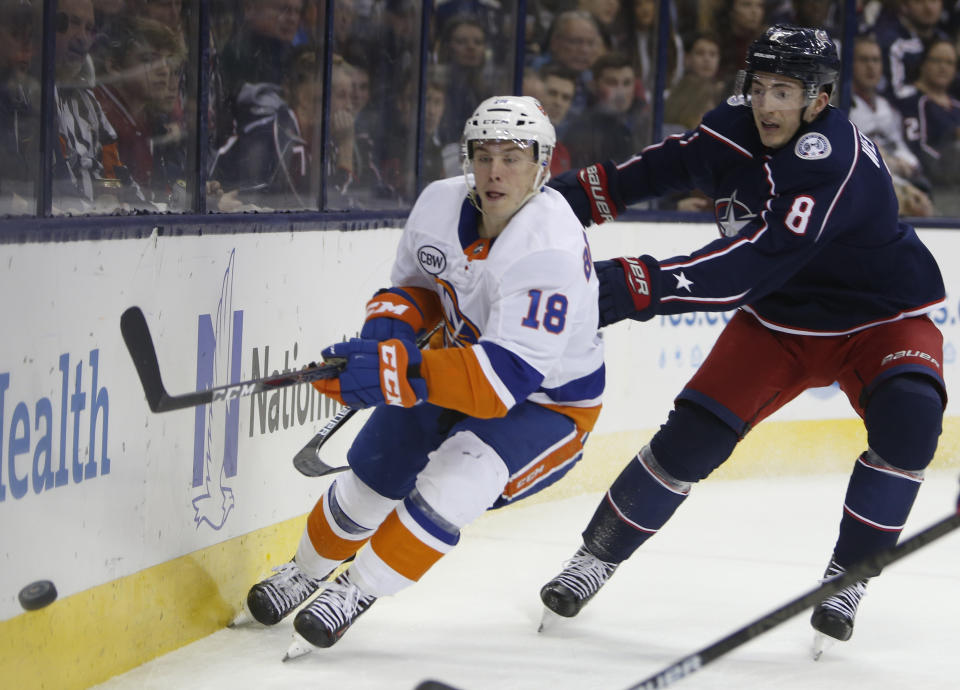 New York Islanders' Anthony Beauvillier, left, passes the puck as Columbus Blue Jackets' Zach Werenski defends during the first period of an NHL hockey game Thursday, Feb. 14, 2019, in Columbus, Ohio. (AP Photo/Jay LaPrete)