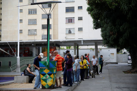 People line up as others charge their phones with a solar panel at a public square in Caracas, Venezuela March 10, 2019. REUTERS/Carlos Garcia Rawlins