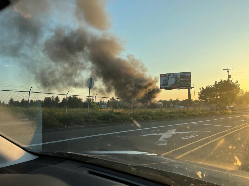 A vegetation fire spreads into some vehicles at Discount Towing and Recovery on Thursday, May 25, 2023, putting up large plumes of smoke.