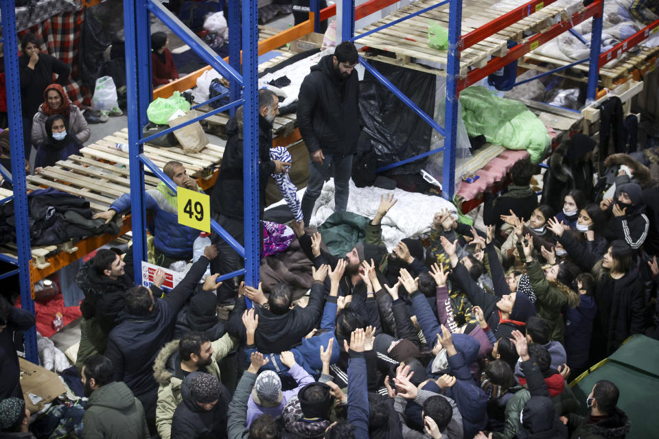 Migrants gather to get warm clothes inside a logistics center at the checkpoint "Kuznitsa" at the Belarus-Poland border near Grodno, in Grodno, Belarus, Sunday, Nov. 28, 2021. The West has accused Belarusian President Alexander Lukashenko of luring thousands of migrants to Belarus with the promise of help to get to Western Europe to use them as pawns to destabilize the 27-nation European Union in retaliation for its sanctions on his authoritarian government. Belarus denies engineering the crisis. (Leonid Shcheglov/BelTA via AP)