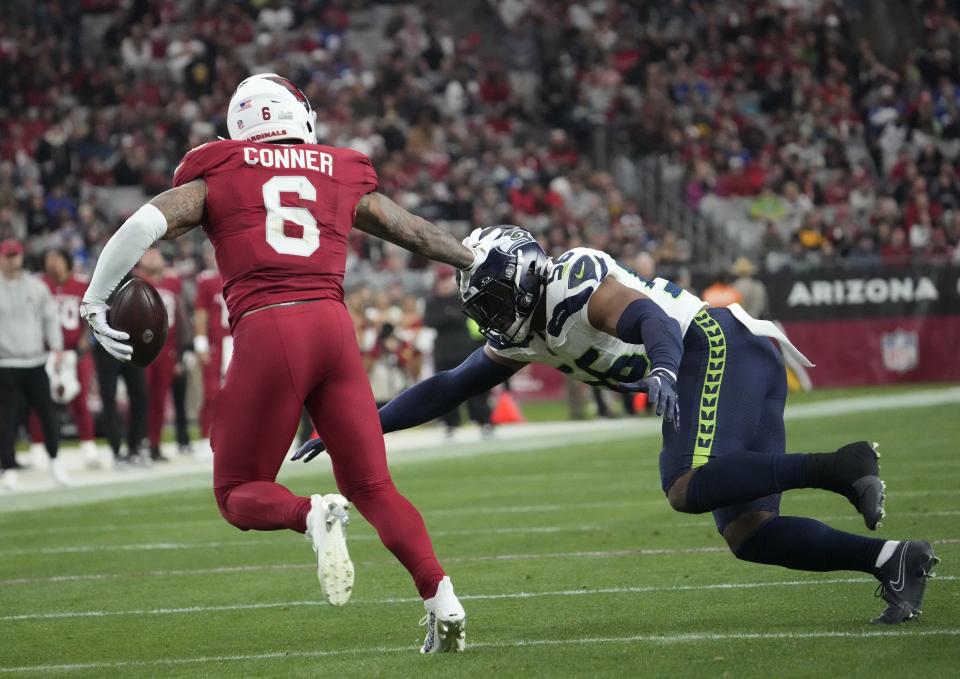 Arizona Cardinals running back James Conner (6) pushes away Seattle Seahawks linebacker Jordyn Brooks (56) during the third quarter at State Farm Stadium in Glendale on Jan. 7, 2024.