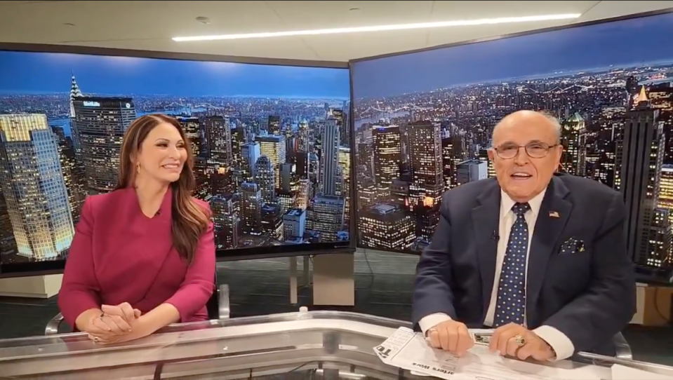 Maria Ryan smiling at Rudy Giuliani during an episode aired on Newsmax (@RudyGiuliani / X)