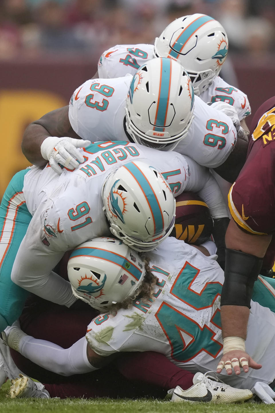 Washington Commanders running back Antonio Gibson, bottom middle, is tackled under Miami Dolphins defensive tackle Christian Wilkins (94), defensive tackle Da'Shawn Hand (93), defensive end Emmanuel Ogbah (91) and linebacker Duke Riley (45) during the second half of an NFL football game Sunday, Dec. 3, 2023, in Landover, Md. (AP Photo/Alex Brandon)