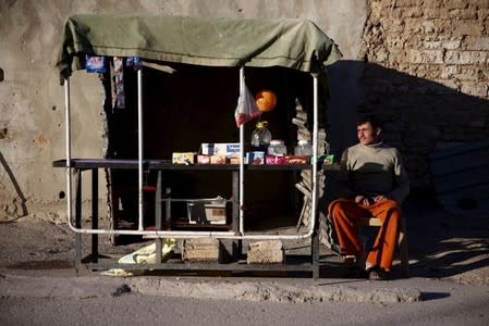 A street vendors sits near his stall in the rebel held Douma neighborhood of Damascus, Syria March 20, 2016. REUTERS/Bassam Khabieh