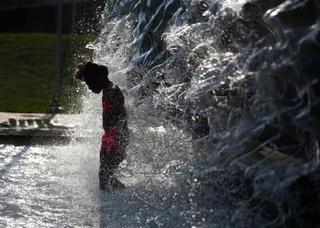 People cool off in a water feature in the Navy Yard neighborhood during a heat wave in Washington