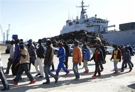 Migrants arrive and are escorted by Italian policemen at the Sicilian port of Augusta near Siracusa March 21, 2014. REUTERS/Antonio Parrinello